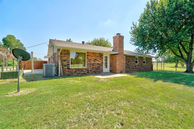 back of house featuring central AC unit and a lawn