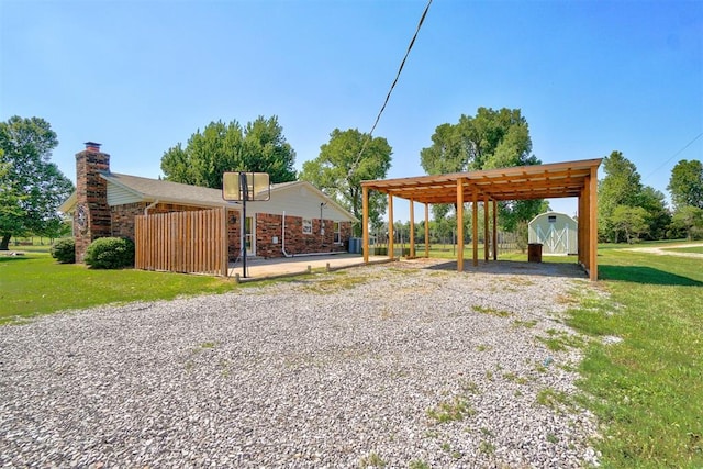 view of community featuring a lawn, a pergola, and a storage shed