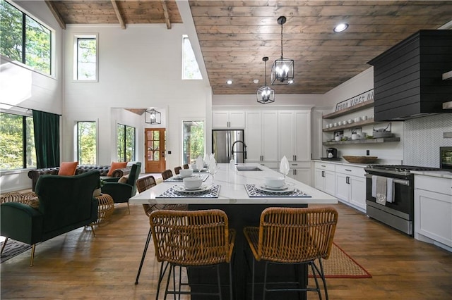 kitchen with a kitchen bar, wood ceiling, stainless steel appliances, a center island with sink, and dark hardwood / wood-style floors