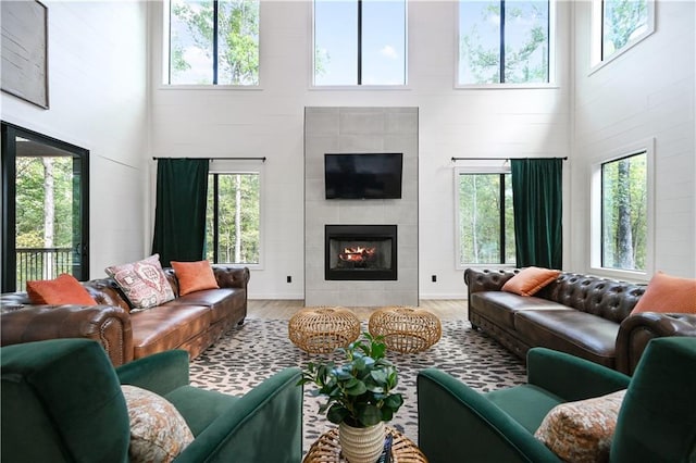 living room with a fireplace, a high ceiling, light wood-type flooring, and plenty of natural light