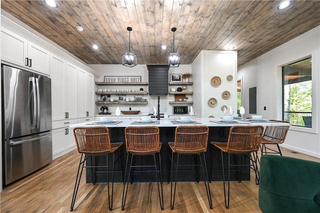 bar featuring stainless steel refrigerator, white cabinetry, wooden ceiling, light hardwood / wood-style flooring, and decorative light fixtures