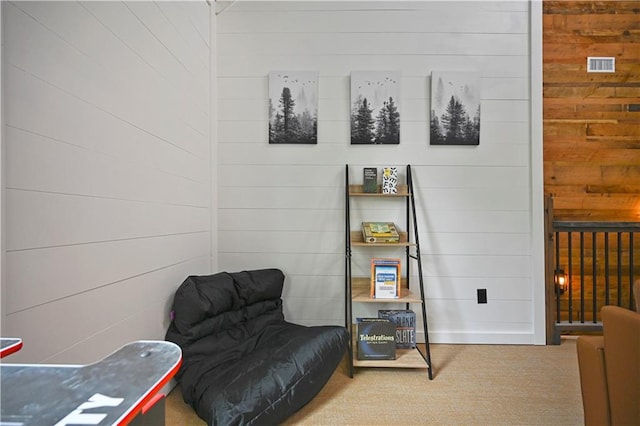 sitting room featuring carpet and wooden walls