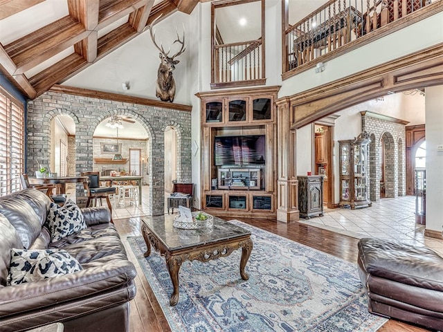 living room with beam ceiling, ornate columns, a towering ceiling, and light wood-type flooring