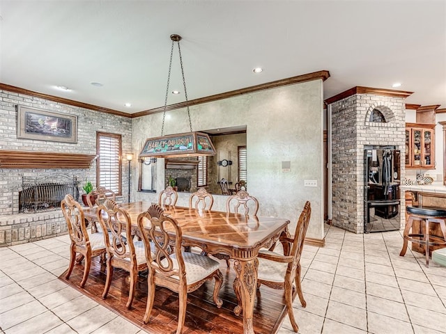 dining space with a large fireplace, crown molding, and light tile patterned flooring