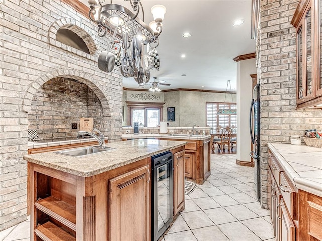 kitchen with crown molding, sink, pendant lighting, a center island with sink, and wine cooler