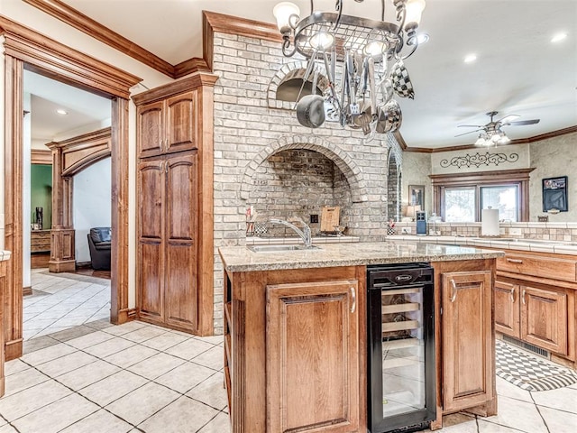 kitchen featuring crown molding, sink, an island with sink, and beverage cooler