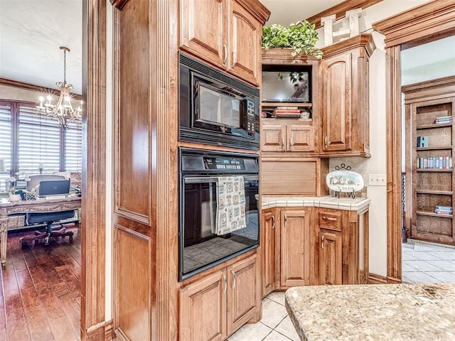 kitchen featuring light hardwood / wood-style floors, black appliances, decorative light fixtures, and an inviting chandelier