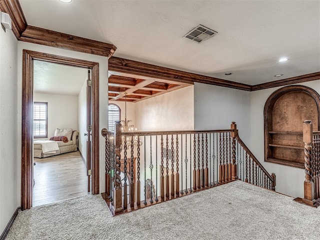 hallway featuring coffered ceiling, crown molding, wood-type flooring, beam ceiling, and a notable chandelier