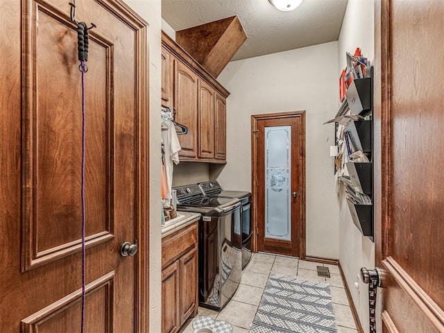 washroom with light tile patterned flooring, cabinets, a textured ceiling, and independent washer and dryer