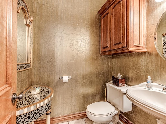 bathroom featuring toilet, sink, and tile patterned flooring