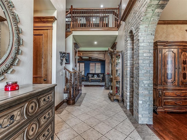 entryway featuring decorative columns, crown molding, and light hardwood / wood-style flooring