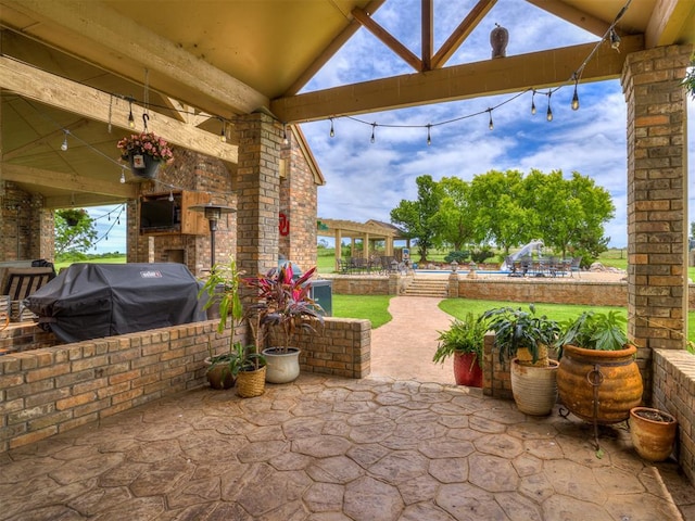 view of patio with area for grilling and exterior fireplace