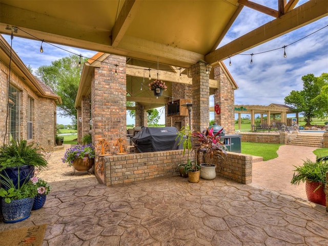 view of patio featuring an outdoor brick fireplace and area for grilling