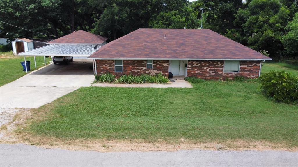 single story home featuring a front yard and a storage shed