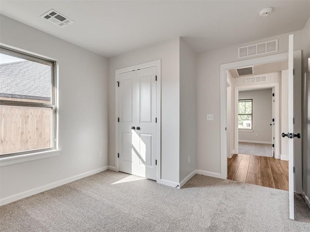 unfurnished bedroom with light colored carpet and a closet