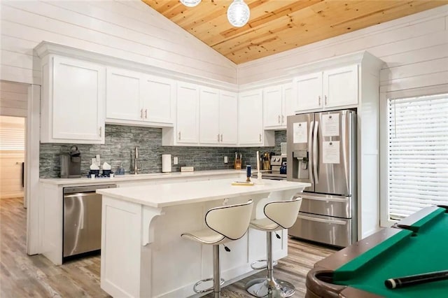 kitchen with appliances with stainless steel finishes, white cabinets, lofted ceiling, wooden ceiling, and a kitchen island with sink