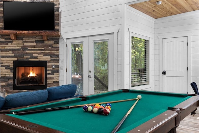 game room featuring wooden walls, wood ceiling, hardwood / wood-style floors, a fireplace, and pool table