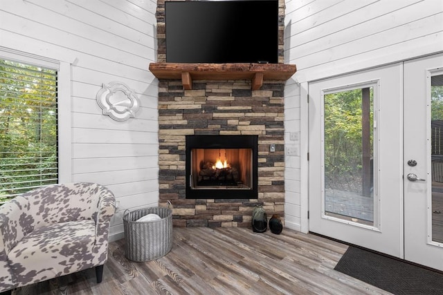 interior space featuring hardwood / wood-style flooring, wood walls, and a stone fireplace