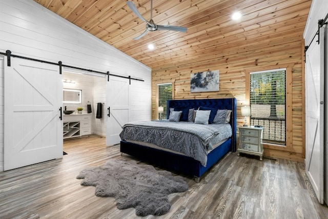 bedroom with wood ceiling, a barn door, wood walls, high vaulted ceiling, and hardwood / wood-style floors