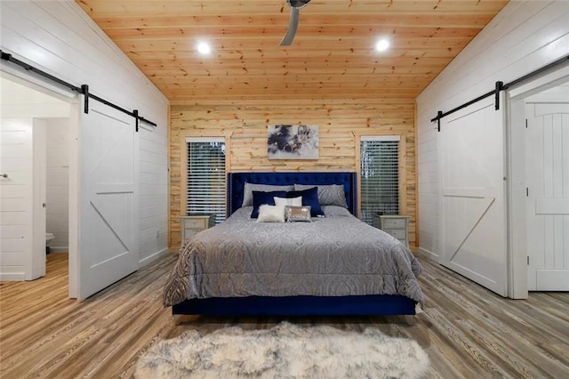 bedroom featuring vaulted ceiling, wooden ceiling, and a barn door