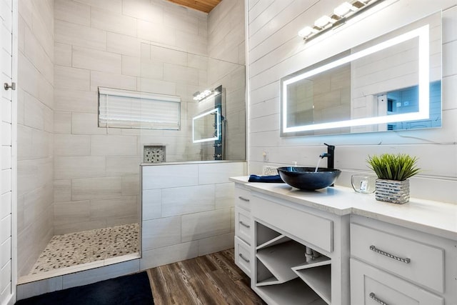 bathroom featuring wood-type flooring, vanity, and a tile shower