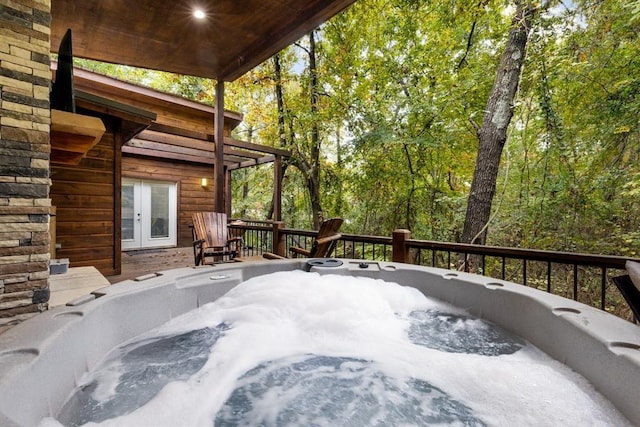 wooden deck with a hot tub and french doors