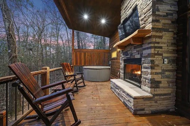 deck at dusk featuring an outdoor stone fireplace