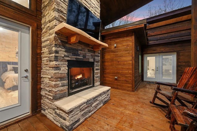 interior details with an outdoor stone fireplace, wood walls, and hardwood / wood-style floors