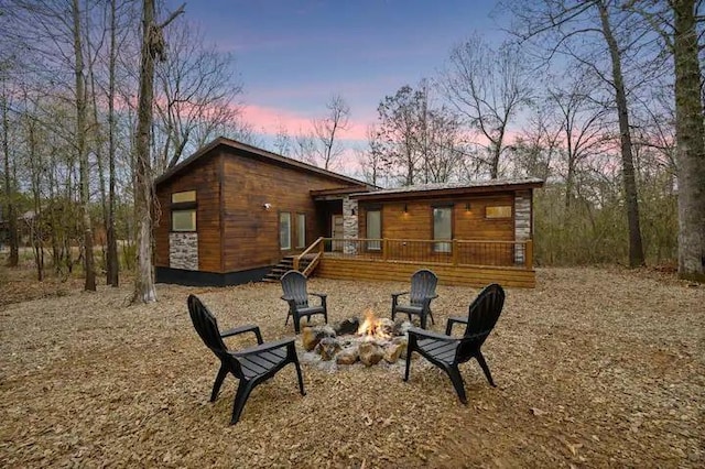 back house at dusk featuring an outdoor fire pit