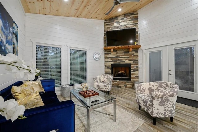 living room featuring wooden walls, high vaulted ceiling, a large fireplace, wooden ceiling, and light wood-type flooring