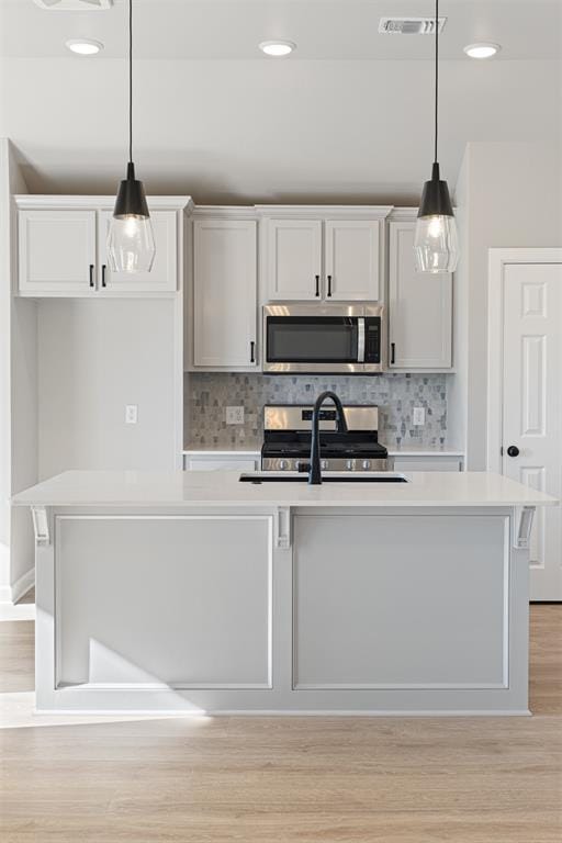 kitchen featuring pendant lighting, stainless steel appliances, and a kitchen island with sink