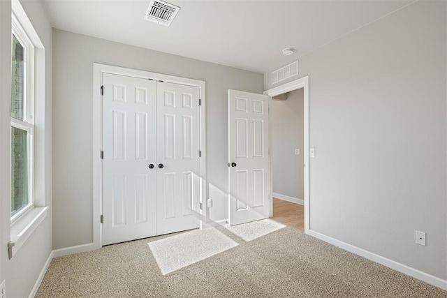 unfurnished bedroom with a closet and light colored carpet