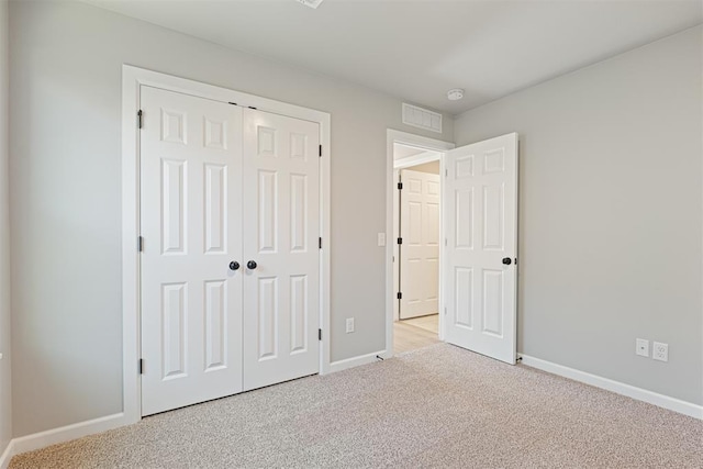 unfurnished bedroom with light carpet and a closet