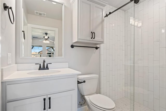 bathroom featuring ceiling fan, toilet, a shower with shower door, and vanity