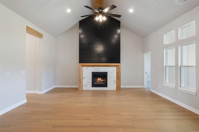 unfurnished living room featuring ceiling fan, a high end fireplace, high vaulted ceiling, and light wood-type flooring