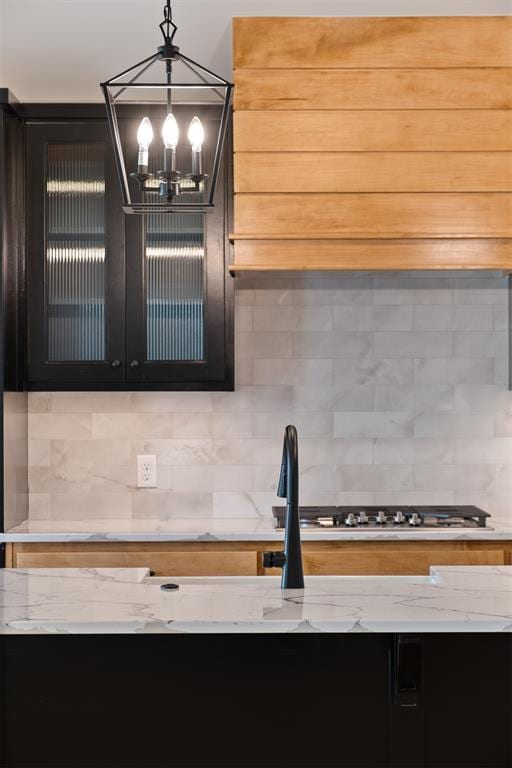 kitchen with a notable chandelier, decorative light fixtures, backsplash, and stainless steel gas stovetop