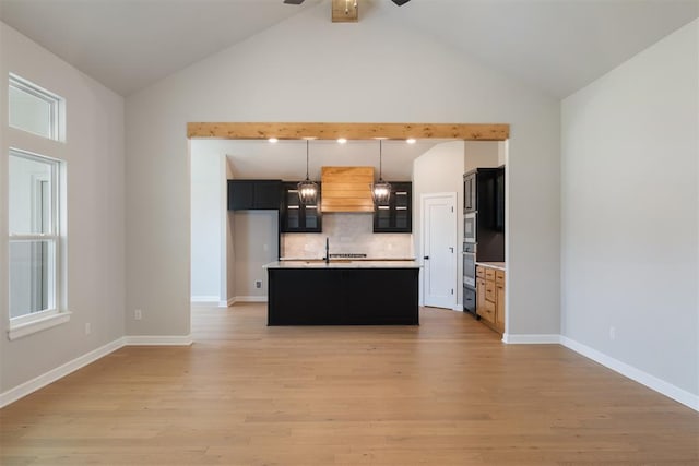 kitchen featuring pendant lighting, a center island with sink, oven, tasteful backsplash, and light hardwood / wood-style floors