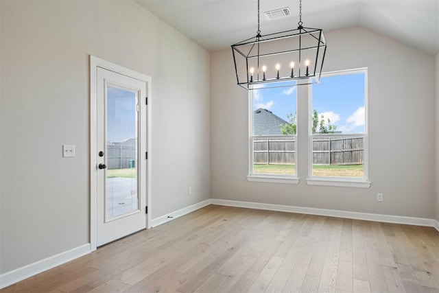 unfurnished dining area with a chandelier, light hardwood / wood-style floors, and vaulted ceiling