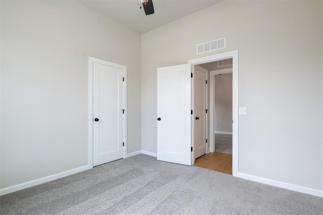 unfurnished bedroom featuring ceiling fan, a closet, and light colored carpet