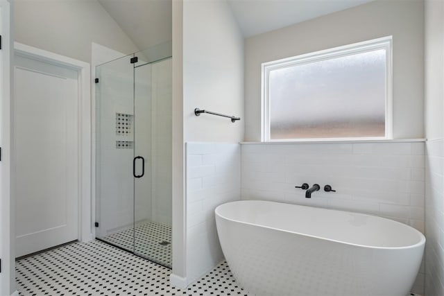 bathroom featuring separate shower and tub, vaulted ceiling, and tile walls