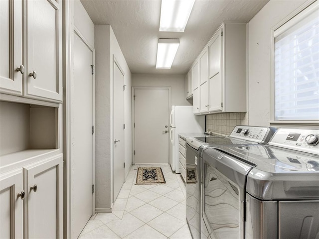 washroom featuring separate washer and dryer, a wealth of natural light, light tile patterned floors, and cabinets