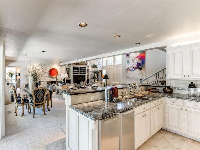 kitchen featuring light carpet, sink, dark stone countertops, tasteful backsplash, and kitchen peninsula