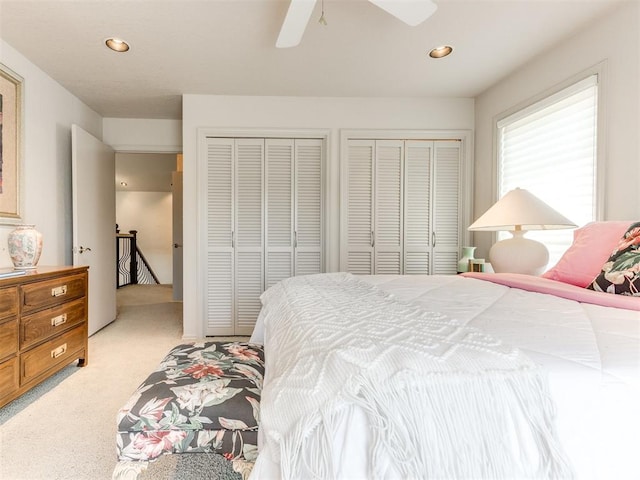 carpeted bedroom with ceiling fan and multiple closets