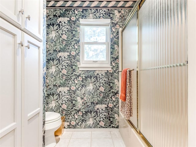 bathroom featuring tile patterned floors, shower / bath combination with glass door, and toilet