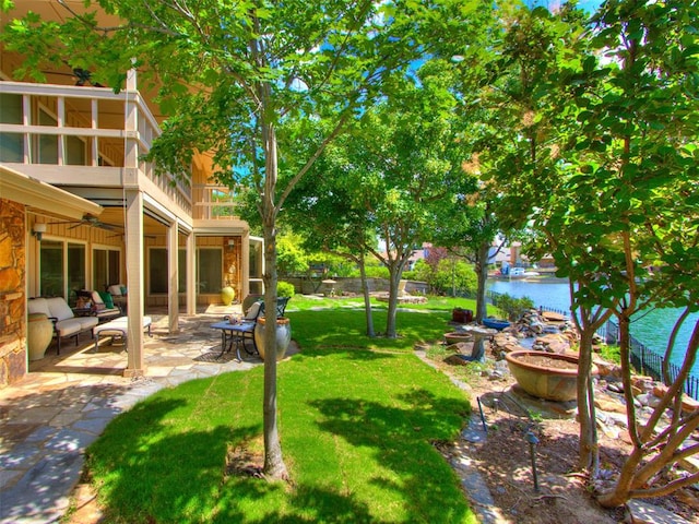 view of yard featuring a patio area, ceiling fan, and a balcony