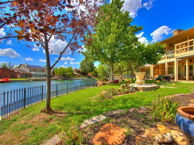 view of yard featuring ceiling fan, a water view, and a balcony