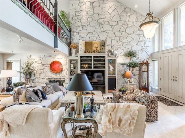 living room featuring a stone fireplace and a towering ceiling