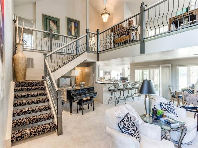 carpeted living room featuring a towering ceiling