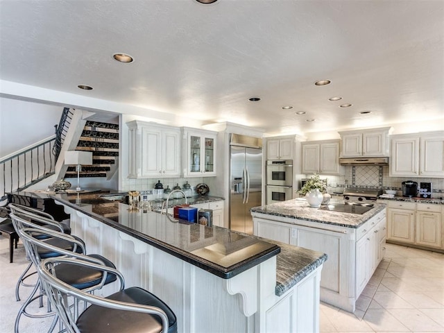 kitchen with stainless steel appliances, a kitchen island, white cabinetry, and a breakfast bar area