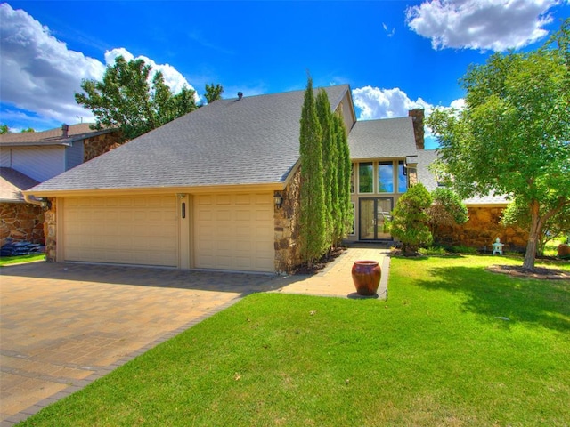 view of front of house with a shingled roof, stone siding, a chimney, and a front lawn